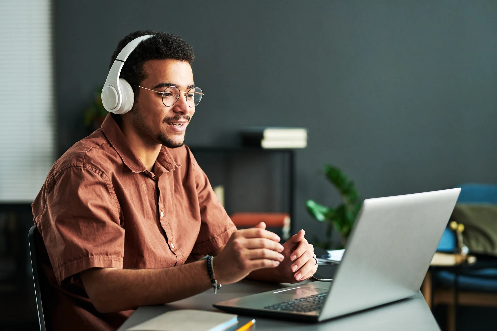 Young confident student in headphones communicating with online audience